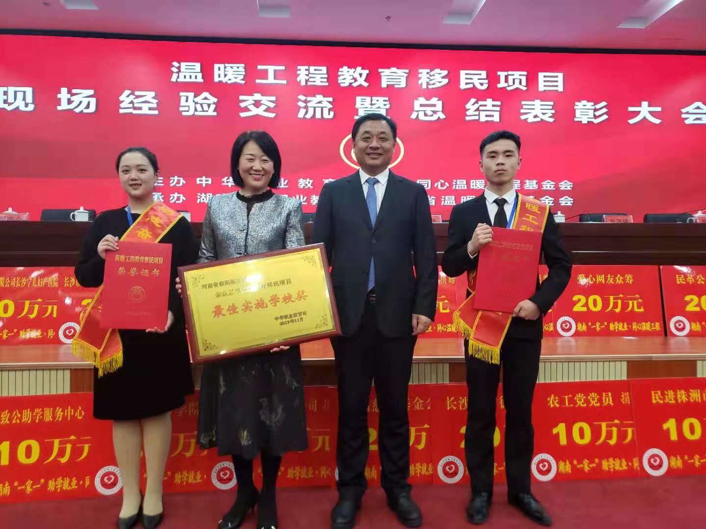 13、2019年11月温暖工程教育移民项目现场经验交流暨总结表彰大会，第十二届全国政协副主席马培华出席会议，学校在会议期间刘品生理事长亲自上台领奖，荣获“温暖工程最佳实施学校奖”.jpg